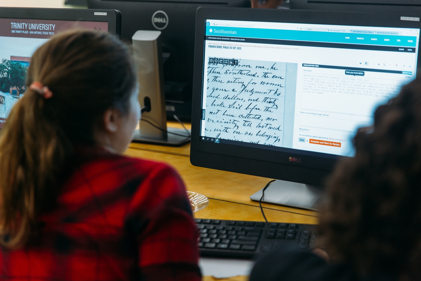 Student looking at computer screen comparing digital version of ancient manuscript and translation next to it