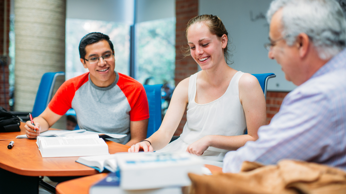 Professor and two students sitting at table talking