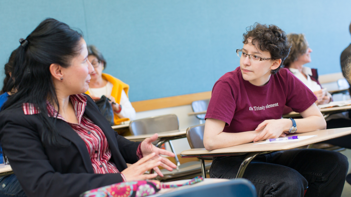 Two students sitting in desks talking