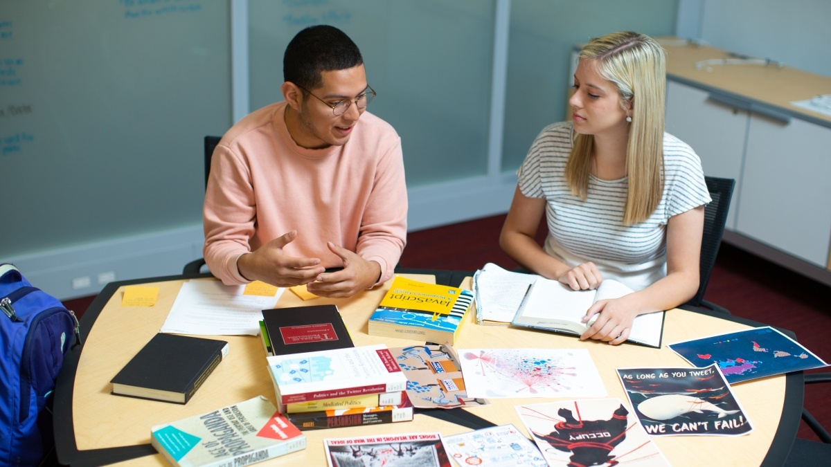 Students around a table with books and work projects