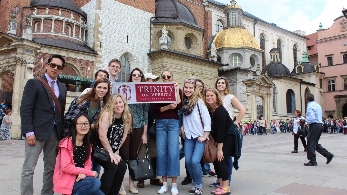 Students abroad pose with Trinity University banner.