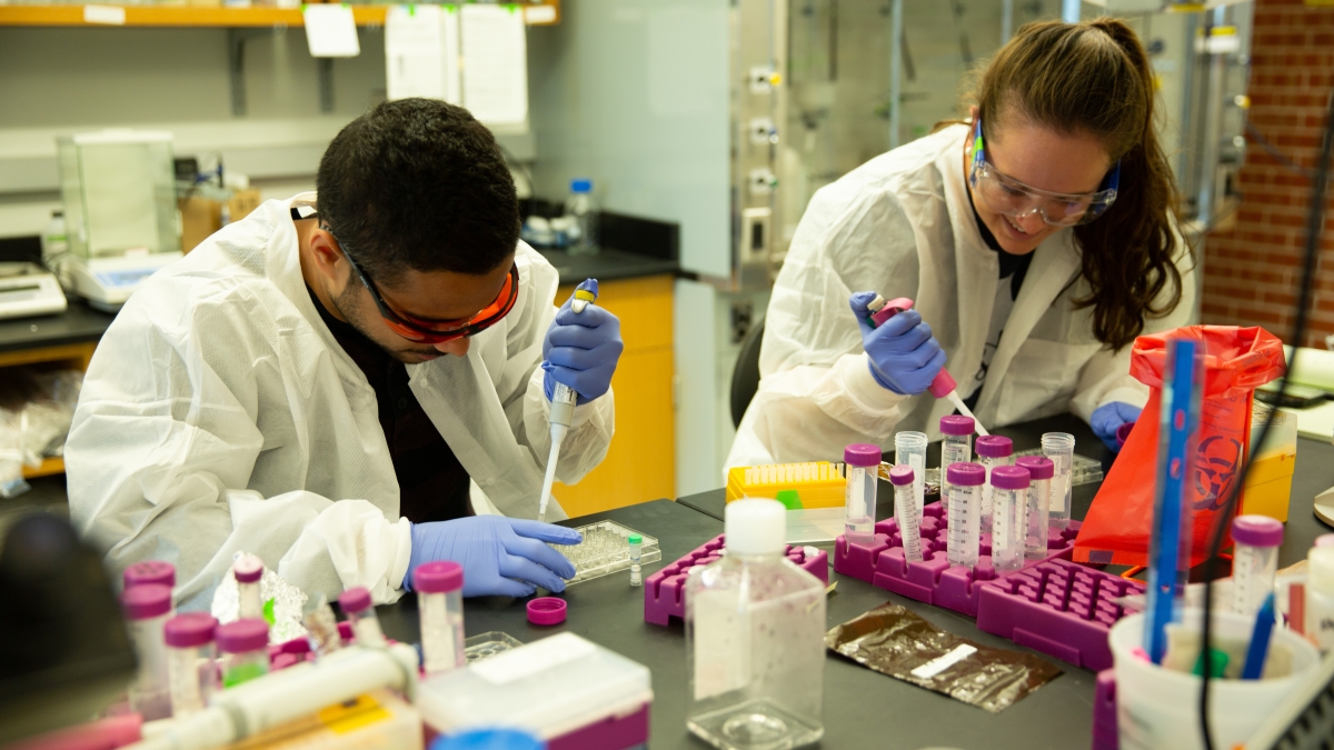 Two students working in a lab mixing fluids