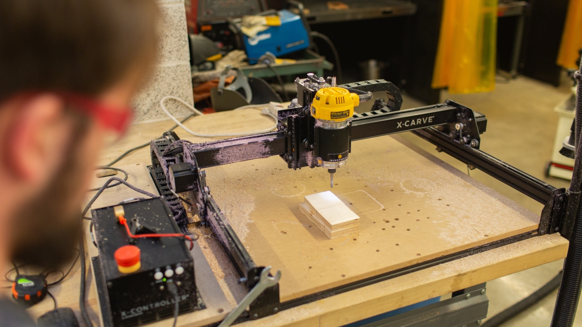 Student watching wood cutting machine work