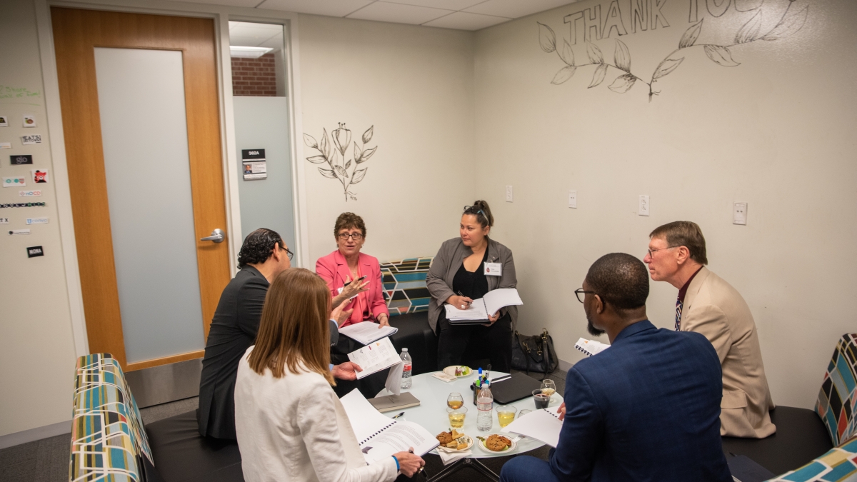 Entrepreneurship faculty gather around a small table 