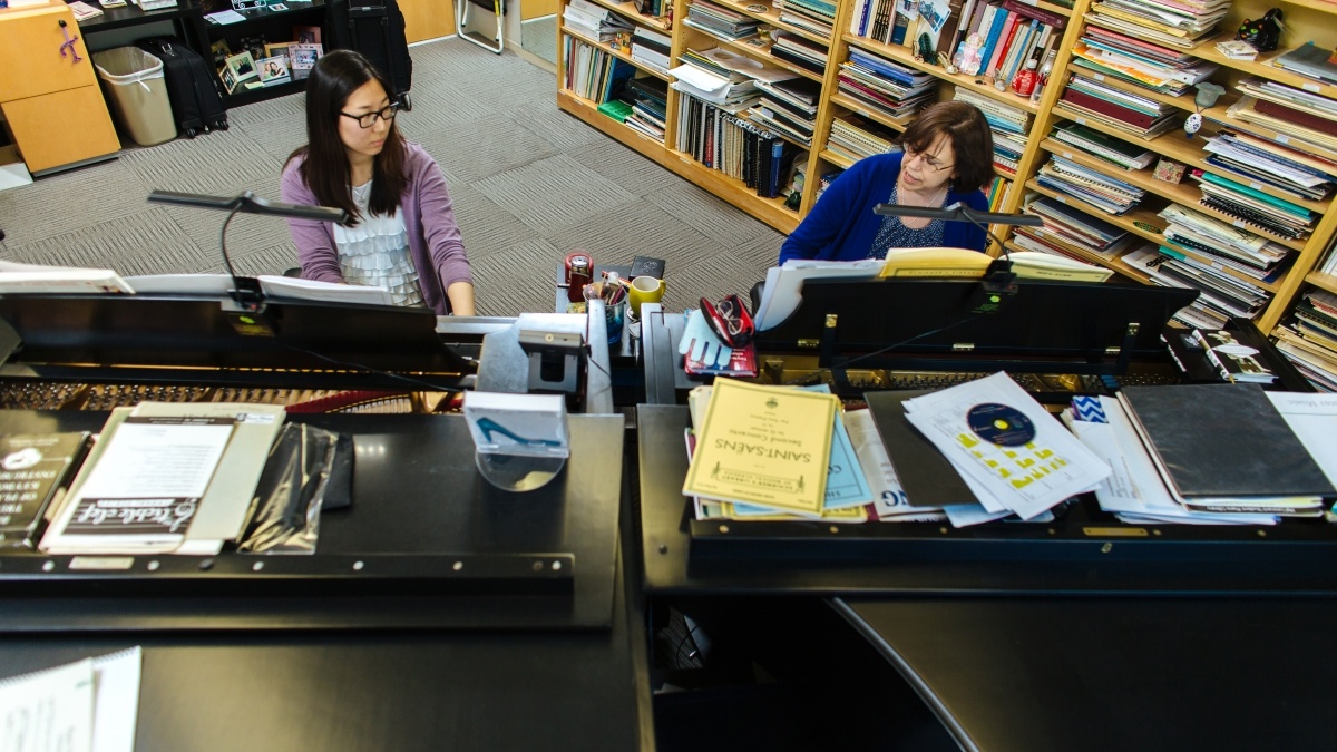 Two people playing pianos next to each other