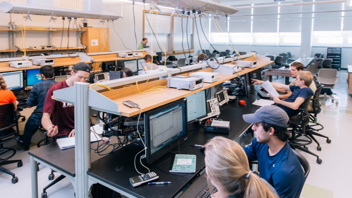 Students in a room, looking at computer screens. 