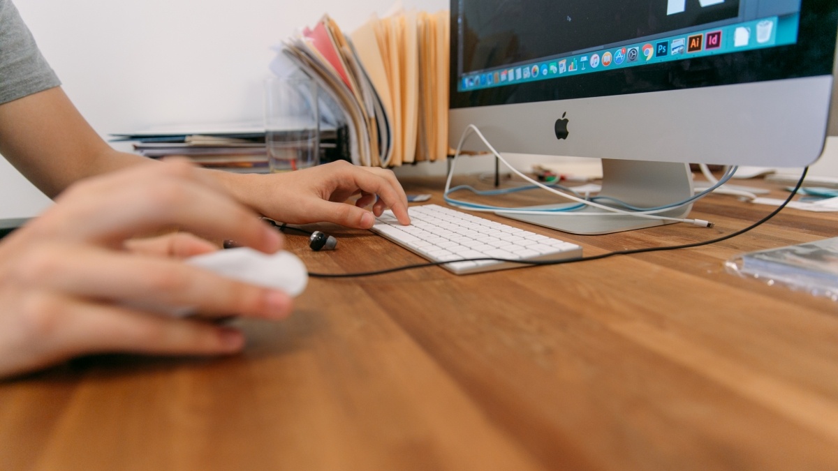 Hand on mouse computer screen visible