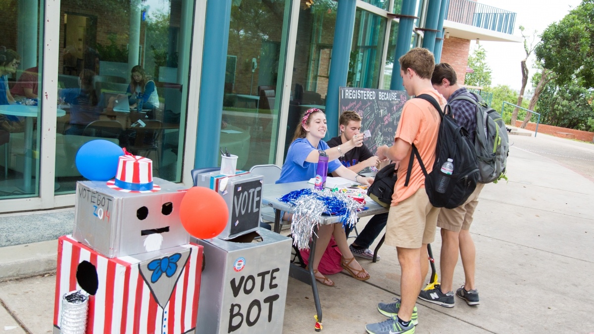 Students at table outside talking to other standing students