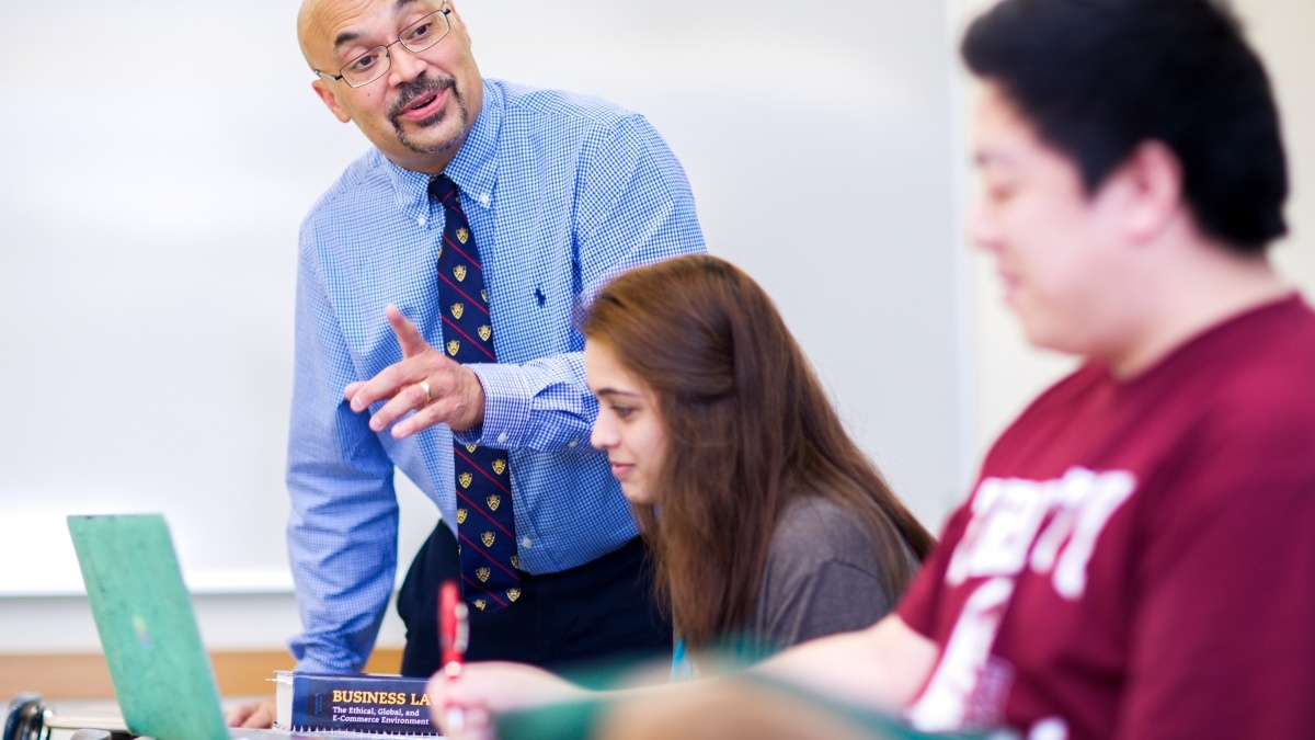 Professor working with two students on their laptops