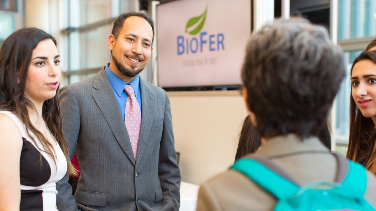 Dante Suarez speaks with two students and a faculty member in the CSI Cube